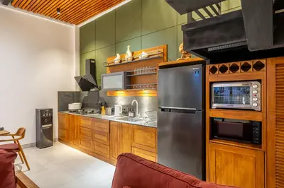a kitchen with wooden cabinets and a stainless steel refrigerator at Lindt - 3BR Villa with Private Pool and Ricefield View in Canggu