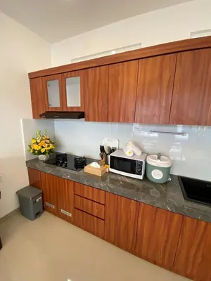 a kitchen with wooden cabinets and a microwave at Arts Ebena Villa Two-Bedroom Private Pool Kuta in Seminyak