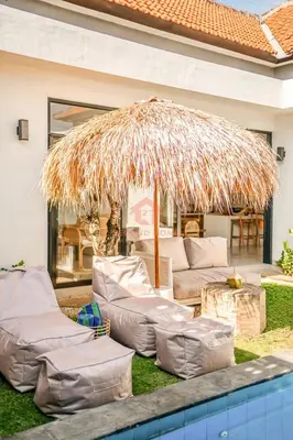 a large straw umbrella sitting next to a pool at Luxury 3BR Umalas Villa Pool & Wi-Fi in Kerobokan