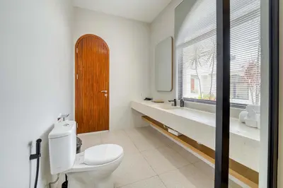 a bathroom with a toilet and a sink and a window at Villa Tébu 3 BR Brand New Villa in Umalas in Kerobokan