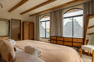 a bedroom with a large bed with two windows at Tuluscoliving villa kuta 2, 4 Bedroom & 5 Bathroom in Ngurah Rai International Airport
