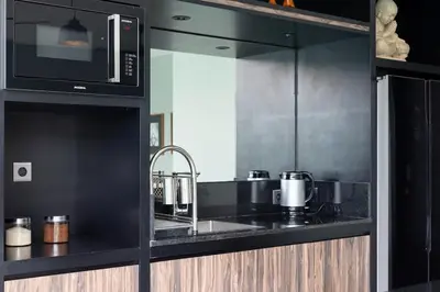 a black kitchen with a sink and a microwave at Villa Orchid Berawa in Canggu