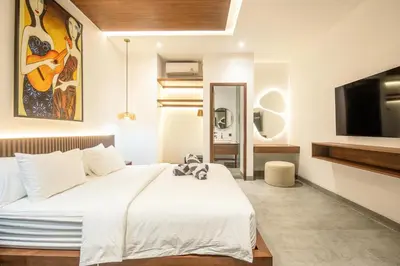 a bedroom with a large white bed with a flat screen tv at Enchanting 5BR Canggu Villa Moments to Sea in Canggu