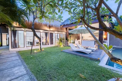 a house with a yard with two chairs and a pool at Karen's Tropical Villa in Seminyak