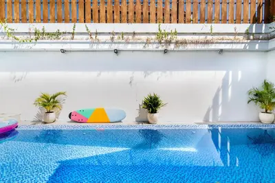 a swimming pool with a surfboard and potted plants at Villa Azure 2 - Private Pool Villa near Seminyak Centre in Seminyak