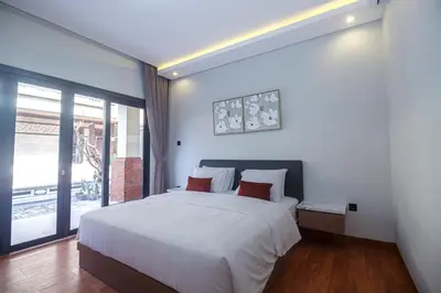 a bedroom with a large white bed and a window at The Hunian in Seminyak