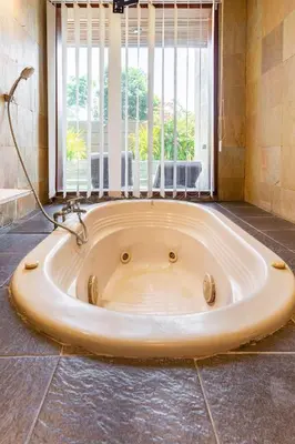 a large bath tub in a room with a window at Kalyca Seminyak 4 Bedroom in Seminyak