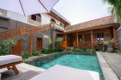 a villa with a swimming pool in front of a house at Kania Rooms & Suite in Seminyak