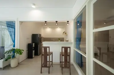 a kitchen with two chairs and a counter with a refrigerator at Casa Sopi - Art Villa 2BR Near Batu Belig Beach in Seminyak
