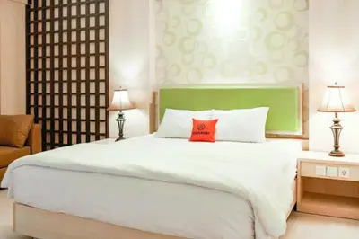 a bedroom with a large white bed with a red pillow at First Home Stay in Ngurah Rai International Airport