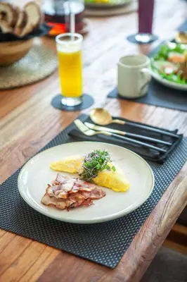 a plate of breakfast food on a wooden table at Luxury 6BR villa Berawa beach in Canggu