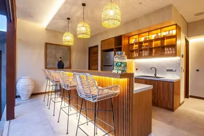 a kitchen with a bar with chairs and a sink at Luxury 6BR villa Berawa beach in Canggu