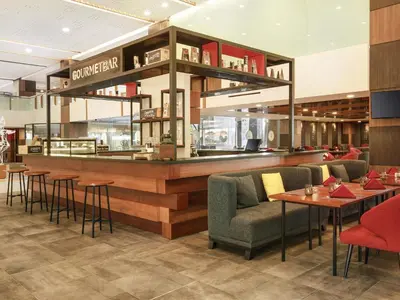 a restaurant with a bar with chairs and tables at Novotel Bali Ngurah Rai Airport in Kuta