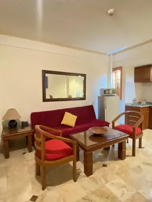 a living room with a red couch and a table at The Coastal Apartment at Jayakarta Residence in Seminyak