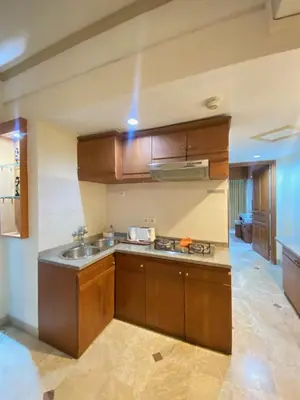 a kitchen with wooden cabinets and a sink at The Coastal Apartment at Jayakarta Residence in Seminyak
