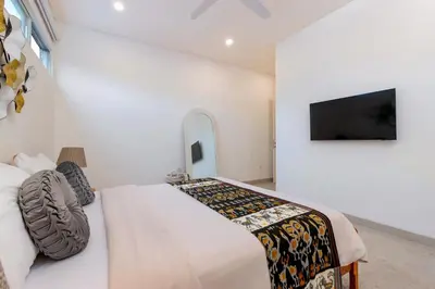 a bedroom with a bed and a tv on a wall at CS 2 Luxurious 3 BR New Villa Near Double Six Beach in Seminyak