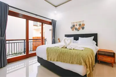 a bedroom with a large bed and a balcony at Nice Villa In Seminyak #YoNa in Seminyak