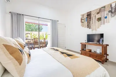 a white bedroom with a bed and a television at RK3, 2 beds villa 15 min walk to Double Six Beach in Seminyak