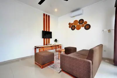 a living room with a couch and chairs and a television at NR Villa, 2 Bedroom Villa Kerobokan in Seminyak