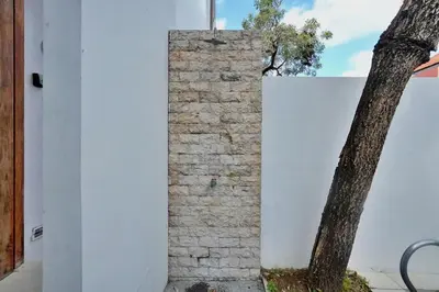 a brick pillar next to a tree next to a white wall at NR Villa, 2 Bedroom Villa Kerobokan in Seminyak