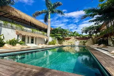 a swimming pool in front of a house with a palm tree at Villa Vela 2 BR - Vela 3 with Private Pool & Rooftop in Seminyak