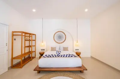a bedroom with a white bed and a wooden shelf at Uma dharma villas 2 in Seminyak