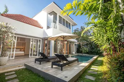 a house with a pool and two chairs and an umbrella at Splendid Villa 3Br Center Seminyak in Seminyak