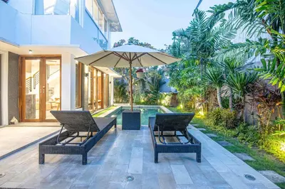 a patio with two chairs and an umbrella at Splendid Villa 3Br Center Seminyak in Seminyak