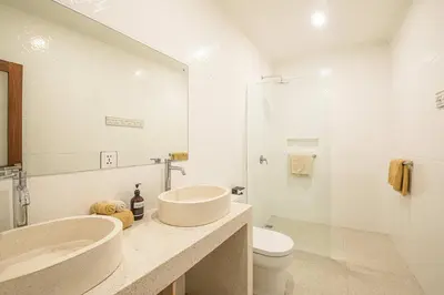a white bathroom with two sinks and a toilet at Splendid Villa 3Br Center Seminyak in Seminyak