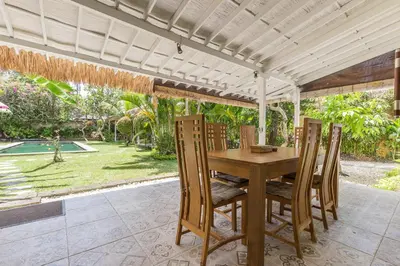 an outdoor dining room with a wooden table and chairs at Villa Sarah 4 chambres près de la plage Oberoi Seminyak in Seminyak