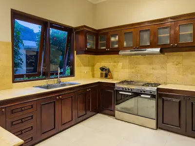 a kitchen with wooden cabinets and a stove at Arjuna Villa 3 Bedroom Villa Seminyak in Seminyak