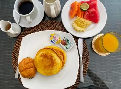a table with two plates of breakfast food and a cup of coffee at Arjuna Villa 3 Bedroom Villa Seminyak in Seminyak