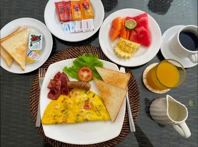 a table with plates of breakfast foods and a cup of coffee at Arjuna Villa 3 Bedroom Villa Seminyak in Seminyak