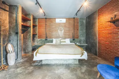 a bedroom with a bed and a brick wall at The Valley Loft in Ngurah Rai International Airport