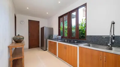 a kitchen with a sink and a stainless steel refrigerator at Alea Estate by Villa Finder in Kerobokan