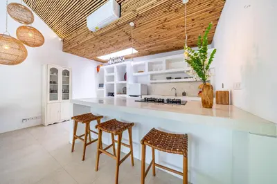 a kitchen with a large white counter with stools at The Oasis Villa in Kerobokan