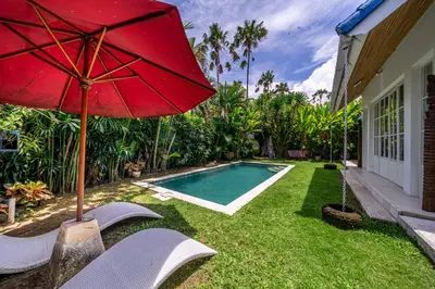 a red umbrella sitting next to a swimming pool at The Oasis Villa in Kerobokan