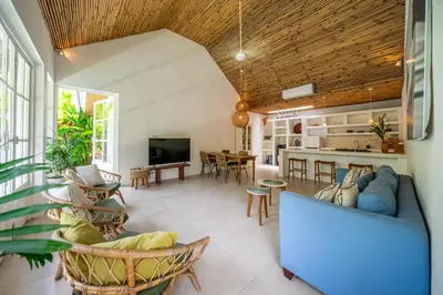 a living room with a blue couch and a kitchen at The Oasis Villa in Kerobokan