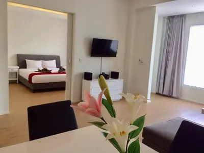 a living room with a bed and a table with flowers at Coast Boutique Hotel in Kuta