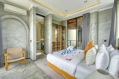 a bedroom with a white bed and a chair at Modern 4BR Industrial - Tropical Escape in Umalas in Kerobokan