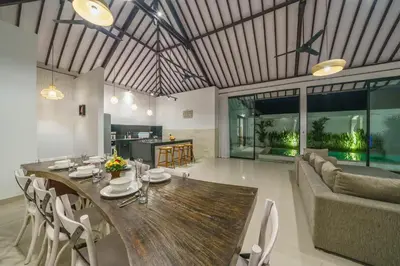 a dining room and living room with a wooden table at Villa Kusuma 2 Seminyak in Seminyak