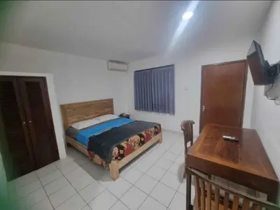 a bedroom with a bed and a table in it at Mulia Legian guest house in Seminyak