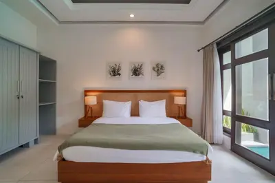 a bedroom with a large bed and a large window at Villa Aura by Maheswara in Seminyak