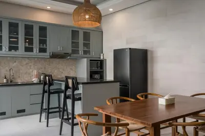 a kitchen with a wooden table and a black refrigerator at Villa Aura by Maheswara in Seminyak