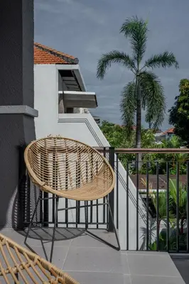 a rattan chair sitting on a balcony with a palm tree at Villa Aura by Maheswara in Seminyak