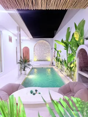 a swimming pool in a room with plants at Luxury Villa Grand Sanur in Sanur