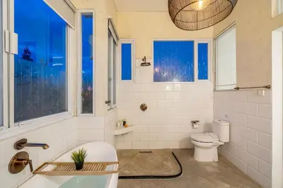 a bathroom with a tub and a toilet and windows at Villa 888 Tropical Heart - 1BR Pool Villa Seminyak in Seminyak