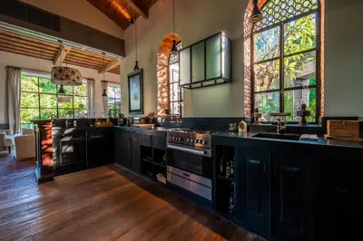 a large kitchen with black cabinets and windows at Villa Yumi by BaliSuperHost in Canggu