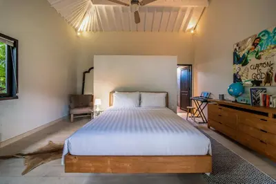 a bedroom with a large bed and a chair at Villa Yumi by BaliSuperHost in Canggu