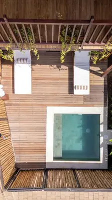 a building with a swimming pool on a wooden deck at Pura Villa in Uluwatu in Jimbaran
